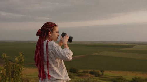 Woman Photographing a Rural Landscape at Sunset