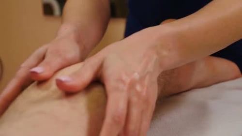 Woman Massaging Man's Leg with Oil, Close Up