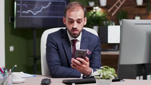 Businessman in Modern Office with Creative Design Having a Video Call Via His Phone