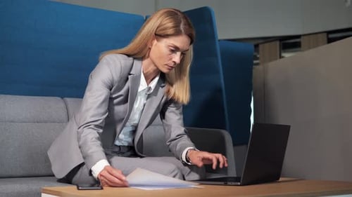 Serious Woman Working on Laptop Computer in Lobby Office Center