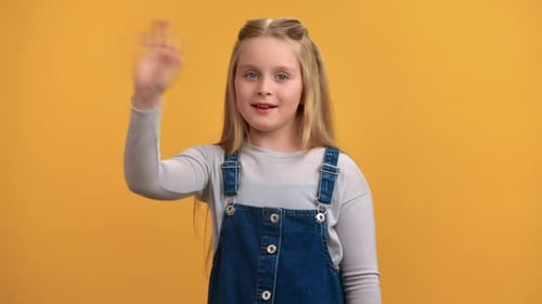 Portrait Happy Cute Baby Girl Greeting Waving Hand with Positive Emotion Posing Isolated on Orange