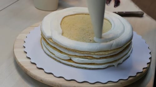 Layered Cake Being Decorated with Creamy Frosting