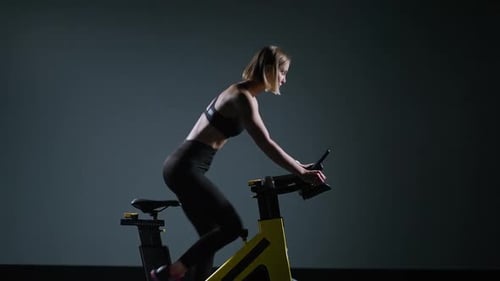 Cycle Training Young Woman is Engaged in Fitness on a Spin Bike Performs Aerobic Endurance Training