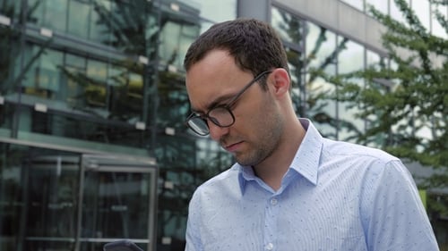 Man Reading Something on The Phone While Walking