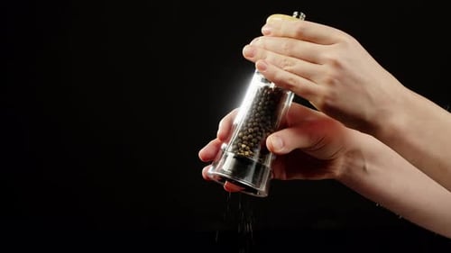 Hands Grinding Pepper with a Mill