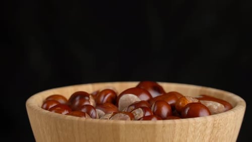Chestnuts in a Wooden Bowl Rotate on Black Background