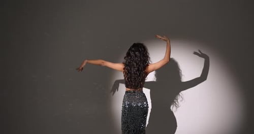 Young Woman with Curly Hair Dancing in a Dark Studio