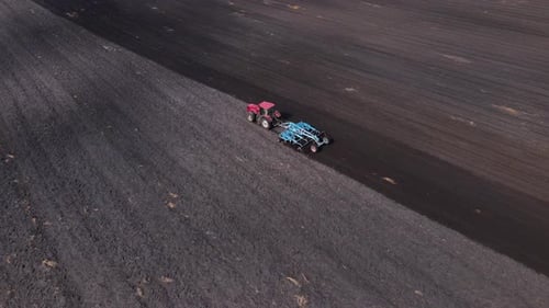Tractor Plows Ground on Cultivated Farm Field