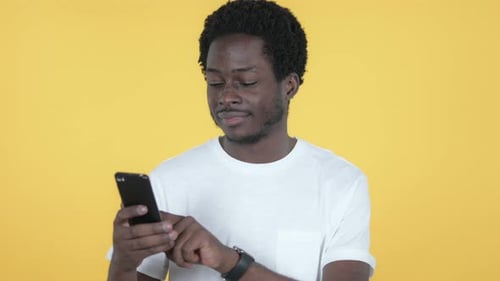 Young Adult Using Smartphone on Yellow Background