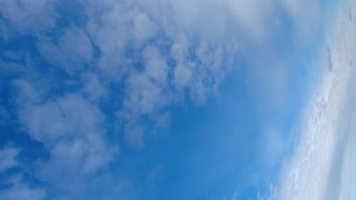 Vertikales Format: Dünne Cumuluswolken durchqueren den blauen Himmel im Zeitraffer