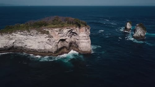 Vue aérienne de vagues s'écrasant sur une petite île rocheuse tropicale sur la côte