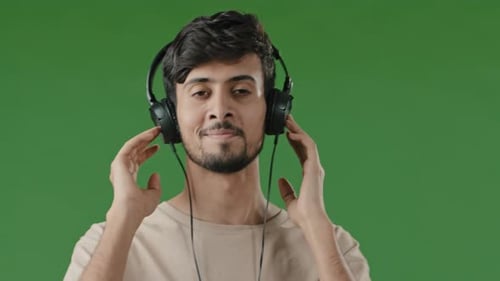 Man Listens to Music on Headphones on Green Screen