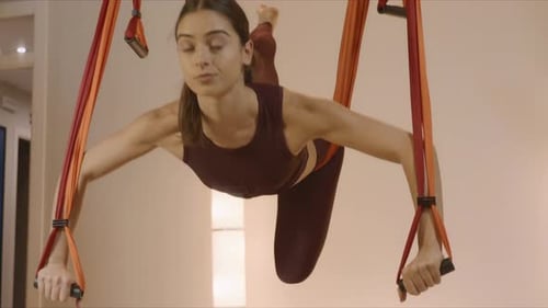 Sporty Woman Practicing Fly Yoga in Studio. Girl Changing Poses in Air at Studio