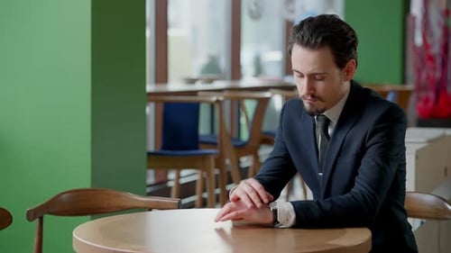 Anxious Serious Caucasian Businessman Checking Time on Watch Sitting in Restaurant