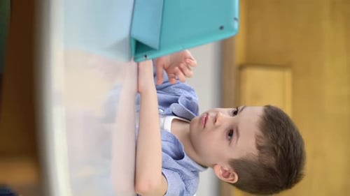 Young Boy Interacting With Tablet at Desk