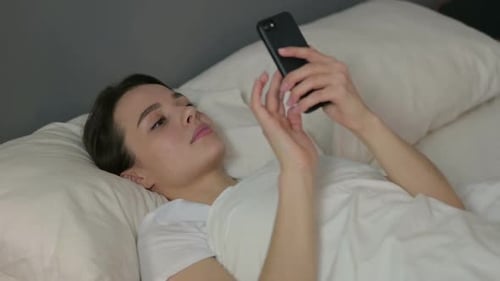 Woman Relaxing in Bed Using Smartphone