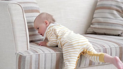 Baby Crawling on Striped Couch in Bright Living Room