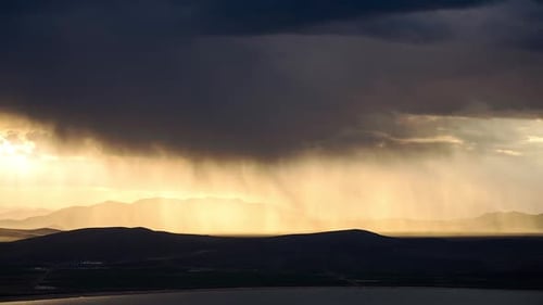 Rainstorm moving over the landscape glowing from the sun near Utah Lake