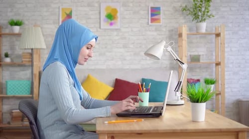 Woman in Headscarf Typing on Laptop at Home