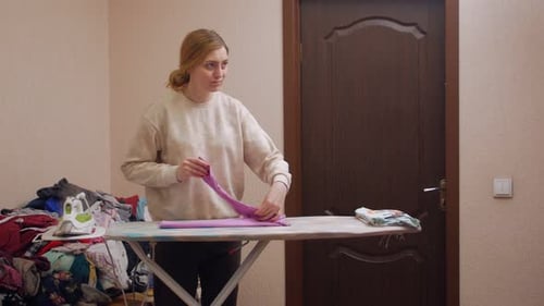 Woman Ironing and Folding Clothes Indoors