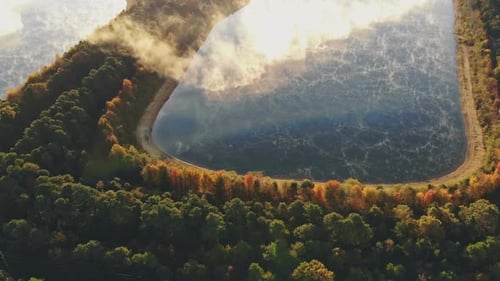 Misty idyllic view of a lake in autumn a fog layer around.