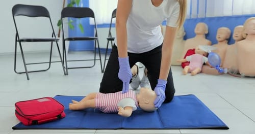 Woman Practices CPR on Baby Mannequin