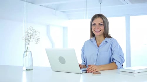 Woman Smiling while Working on Laptop Computer