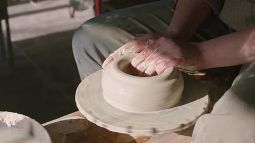 Potter modélise le côté d'un bol en argile humide
