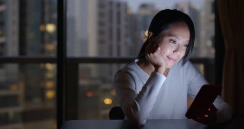 Woman Using Mobile Phone Indoors at Night