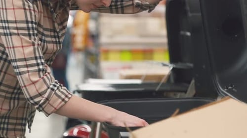 the Girl's Hand in a Plaid Shirt Considering a Grill in the Store