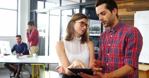Coworkers Reviewing a Tablet in Modern Office Setting