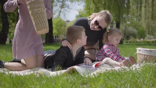 Family Picnic Reading on Sunny Green Grass