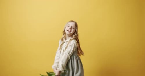 Happy Girl Dancing with Flowers on Yellow Background