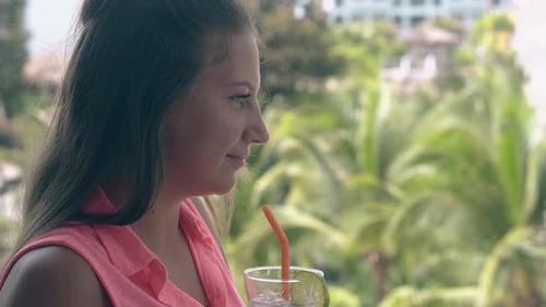 Girl Drinks Cocktail Enjoys Beautiful View on Tall Green Palms