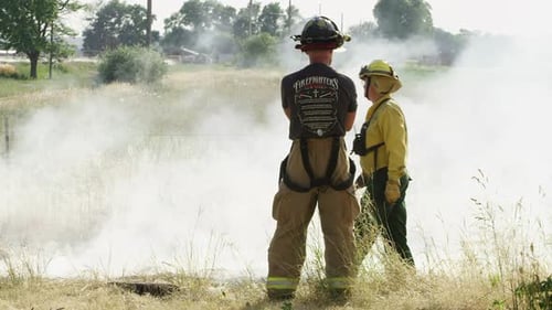 Firefighters Surveying Smoke in Rural Grassy Field