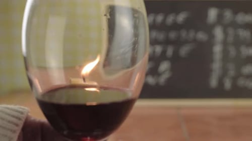 Hand holding glass of red wine with candle reflections close up shot