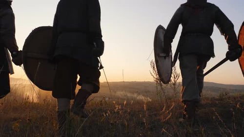 Silhouettes of Viking Warriors Gather and Stop in the Field and Watch the Beautiful Sunset.