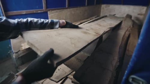 Worker Stacking Wooden Planks in a Workshop