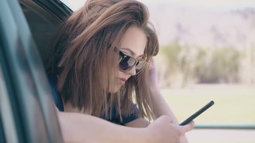 Woman Looks at Smartphone in Car