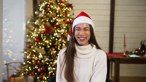 Young Woman Smiles in front of Christmas Tree