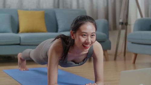 Asian Athletic Female Doing Yoga In Forearm Plank Pose On The Mat At Home With Online Coach