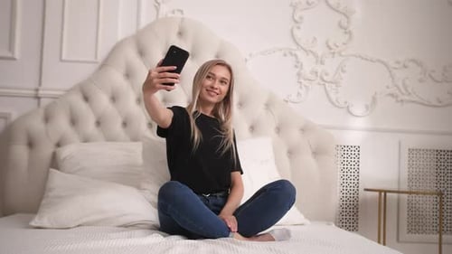 Smiling Woman Using Phone on Bed at Home