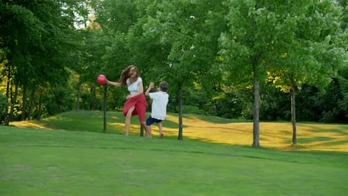 Mother and Children Playing with Ball in Meadow. Family Enjoying Time Outside