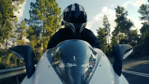 POv shot of a man riding on a white sports motorcycle on a curved road