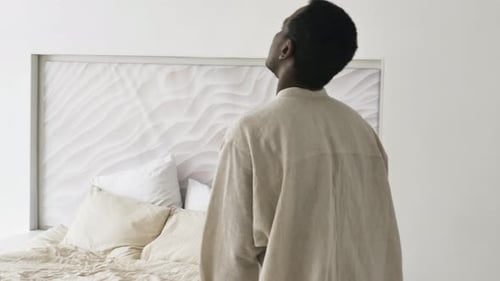 Tired AfricanAmerican Man Trudges to His Bed and Falls Exhausted on a Soft Cozy Bed Lies with His