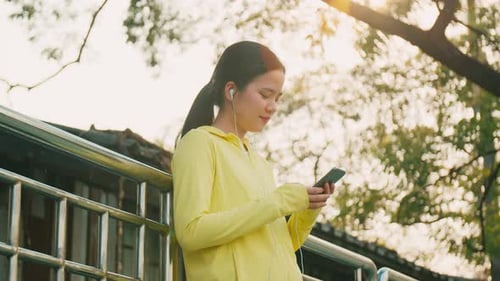 Young Woman Using Mobile Phone in Golden Sunlight