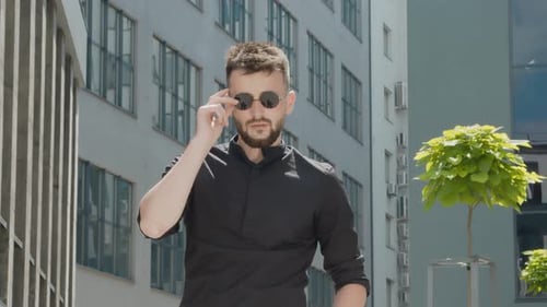 Man Putting on Sunglasses Outside Urban Building