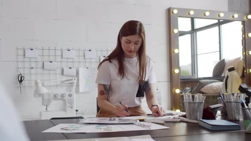 Female Designer Drawing Fashion Sketch in Sewing Studio