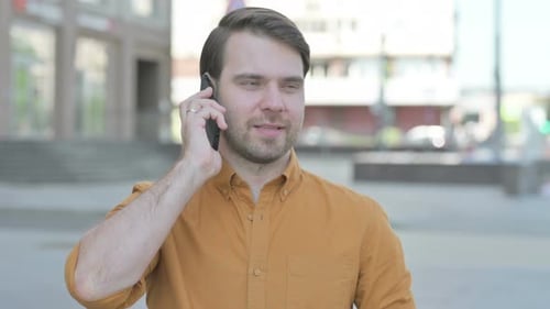 Young Adult Talking on a Cell Phone Outdoors