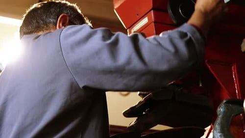 Man Operating Large Red Machine in Factory